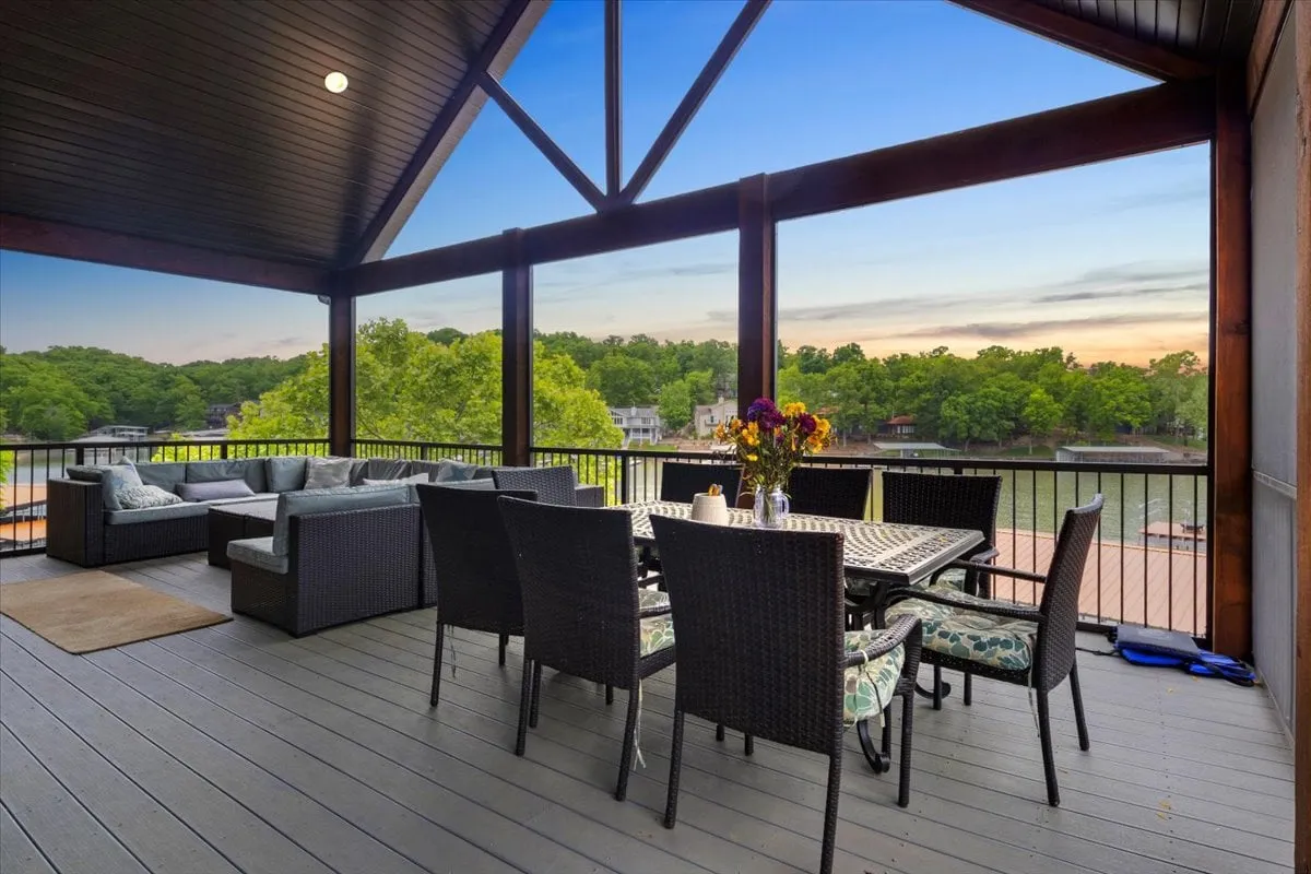 An exterior dining area with a table and chairs is set under the open sky, overlooking the water. The space is designed for both intimate dinners and lively gatherings, with a cheerful, relaxed mood that suggests evenings under the stars or sunny morning meals with a lake view.
