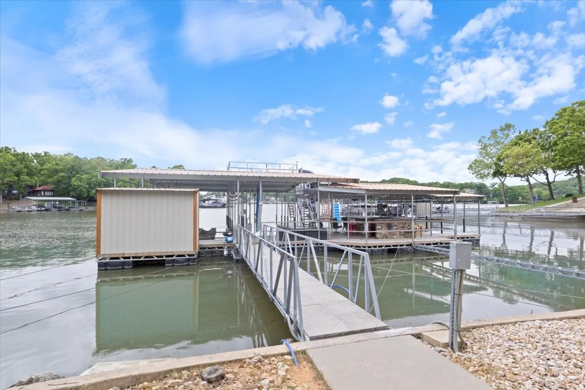 A serene shot of the private boat dock nestled among trees, overlooking calm water and marina-style facilities. The dock is an inviting setting for boating, fishing, and enjoying the tranquil atmosphere, with sunset colors enhancing the mood.