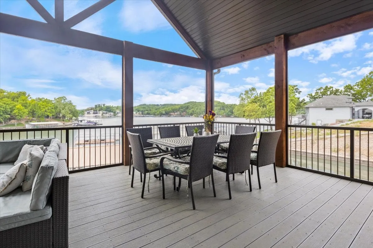 Featuring a dining table and welcoming outdoor seating area with a stunning lake view and lush greenery, this image embodies the experience of deckside dining, whether for morning coffee or sunset dinners. The scene hints at the multi-level decks described in the text and highlights the serenity and beauty of al fresco meals.