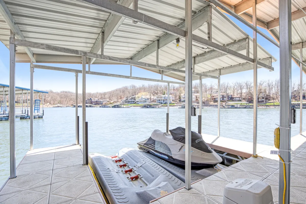 A dock with jet skis parked at its edge offers a dynamic waterfront perspective. The water is peaceful, but the presence of jet skis emphasizes the thrill of water sports and the variety of activities possible right from the dock.