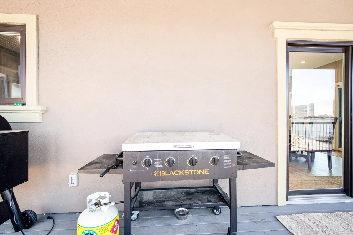 This image highlights a grill set up in an inviting outdoor setting, with the open air and view through the door suggesting ease of access and a natural transition from inside to outside. The space is clearly designed for barbecuing and informal gatherings, implying ample room for guests to socialize around the grill.