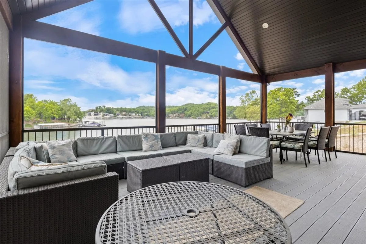 An outdoor entertaining area featuring a large sectional sofa, dining table, and sweeping views of the lake. The setup is perfect for gatherings, barbecues, or relaxing after a day exploring local attractions.